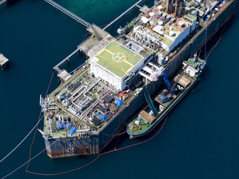 Aerial view of a Floating Storage and Offloading ship with a helipad and industrial equipment moored in the deep blue waters of Buleleng Regency, Bali, Indonesia.