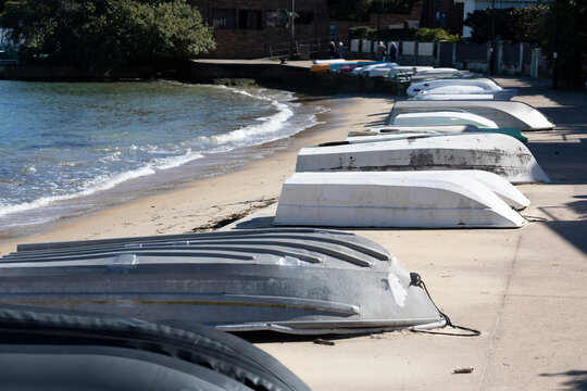 dinghies arranged along the beach at Watson's Bay waterfront on Sydney Harbor on sunny day. They are used to row out to large boats on moorings