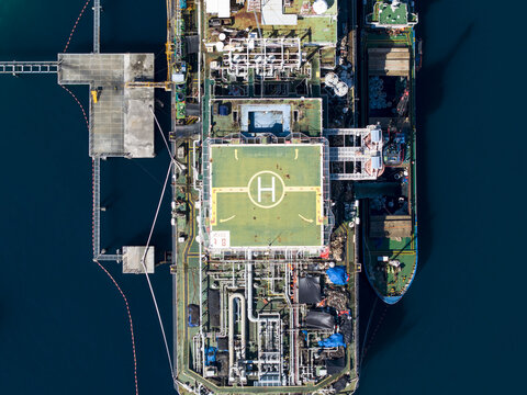 Aerial view of a Floating Storage and Offloading Ship with a helipad, industrial piping, and a support vessel moored in the sea of Buleleng Regency, Bali, Indonesia.