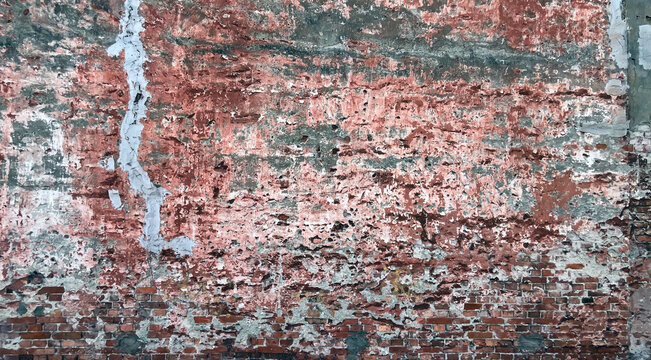 Close‑up of a heavily weathered red brick wall with peeling layers of faded paint, exposed masonry, cracks, and erosion, creating a richly textured urban decay background.