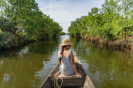 Woman relaxing at the bow of a wooden boat, Tam Giang mangrove canal, Hue, Vietnam