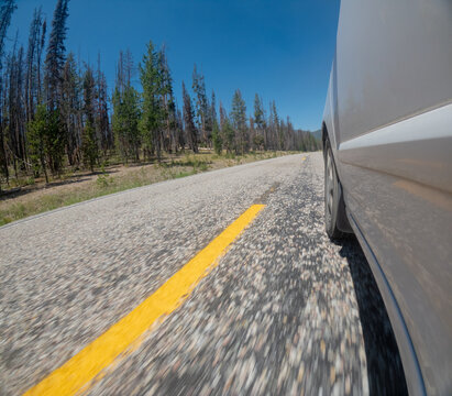 White car moves along a blurred gravel road with a yellow line