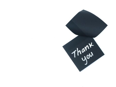 Thank you handwritten phrase on a black adhesive note isolated on white background with copy space. Minimalist concept for customer appreciation, gratitude note, or polite greeting message
