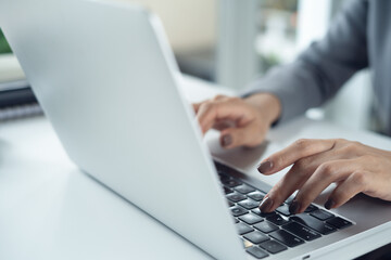 Close up of business woman hands working, typing on laptop, surfing the net on office desk, corporate business concept © tippapatt
