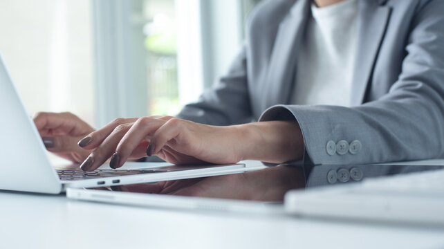 Business woman working on laptop with digital tablet on office desk, close up