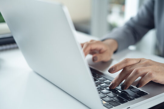 Close up of business woman hands working, typing on laptop, surfing the net on office desk, corporate business concept