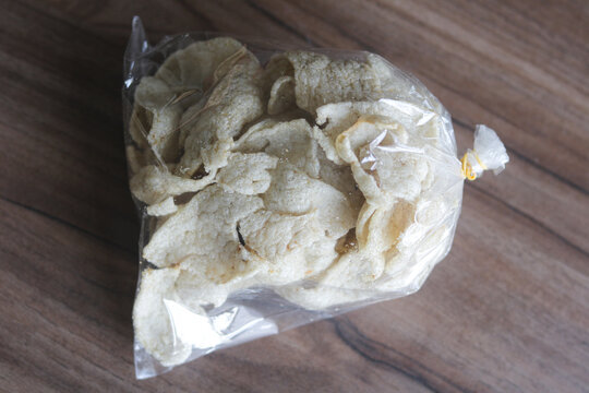 Traditional fish crackers packaged inside a clear plastic bag on a wooden surface.