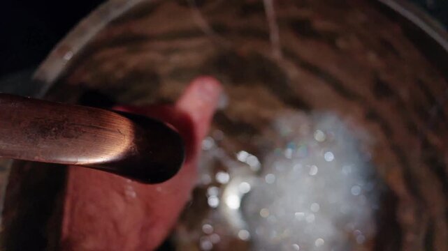 A male hand washing with running water in a copper sink creating soapy bubbles during a handwashing ritual with motion.