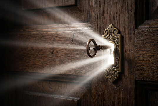 Antique skeleton key unlocking wooden door emitting bright light rays