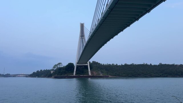 BATAM, INDONESIA - AUGUST 14 2026: Low angle view of the majestic Barelang Bridge (Tengku Fisabilillah) showing its cable-stayed architecture, concrete pylon, and the underside of the deck over the ca