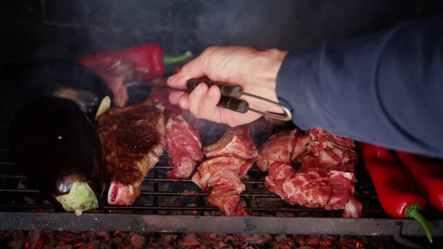 Close up of meat and vegetables cooking on a barbecue grill with smoke rising.
