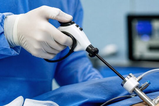 Gloved hand operating laparoscopic instrument in surgery