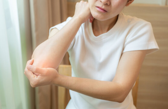 Cropped shot view of Asian woman holding and massaging her elbow because of pain. Conceptual of woman suffering painful caused by injury or overuse.