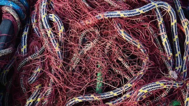 Close-up shot of tangled fishing nets and ropes in a pile on a boat deck.