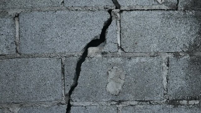 Weathered Grey Concrete Block Wall Large Diagonal Crack Close Up Urban Decay Structural Damage Grunge Texture Background Portrait