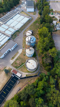 Aerial view of the Assago wastewater treatment facility featuring large anaerobic digesters for sludge treatment and biogas production, set in Assago, Lombardy, Italy.