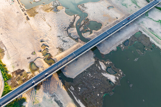 Aerial shot of a bridge spanning a shallow river with exposed sandy riverbed and small water pools.