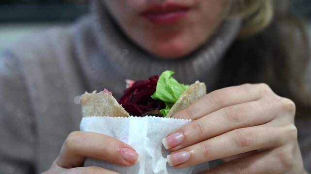 Woman eating healthy pita bread sandwich with fresh vegetables.