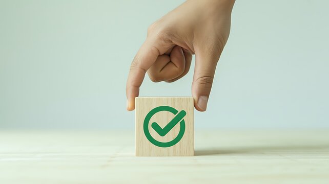 Hand touching a wooden block with green checkmark symbol representing approval, success, and correct choice