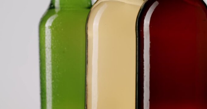 Three unopened beer bottles of different types and colors, including lager, ale, and cider, Different beer bottles slowly rotating on white background. different glass bottles of fresh craft beer