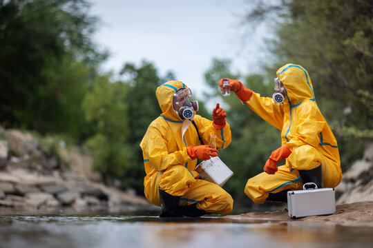Environmental scientists wearing protective suits collect and examine water samples from a natural water source during field research. Researchers perform water quality testing to detect contamination