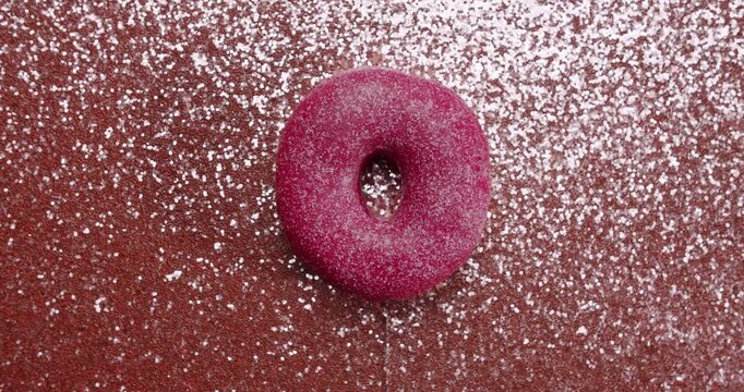 Colorful variety of fresh sweet donuts with different glazes and sprinkles changing one after another on a black, white, and red sparkling background in a continuous loopable sequence. stop motion
