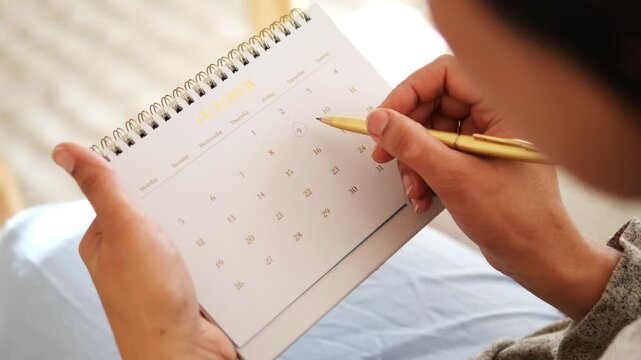 Writing in a calendar with a pen in a home setting