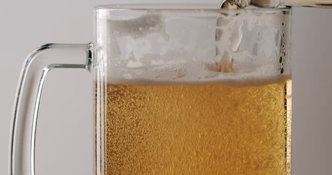 Fresh cold light beer pouring into a glass mug, creating bubbles and a frothy head. Slow-motion close-up shot of the refreshing alcoholic beverage isolated on a clean white background