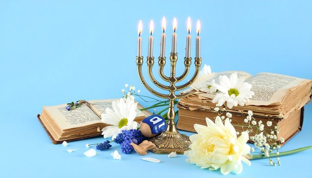 Hanukkah menorah with burning candles, old books, and white flowers on blue background