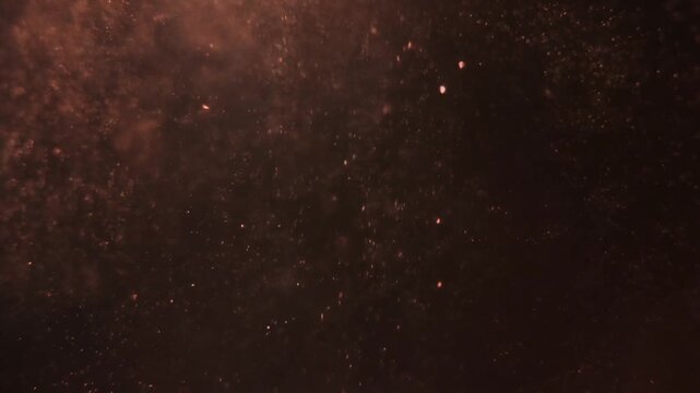 Fine rose-gold metallic dust particles drift upward in a slow continuous stream through dark viscous liquid, catching dramatic side lighting against total black &mdash; loop perfect for luxury overlays.