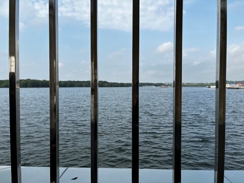 Ocean view through wooden window frame with clear blue sky and calm water horizon