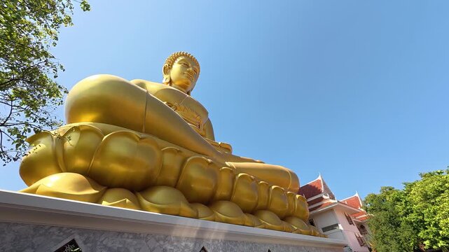 The majestic golden Buddha statue at Wat Paknam Bhasicharoen temple in Bangkok, Thailand, towering above the temple complex in a striking and peaceful setting.