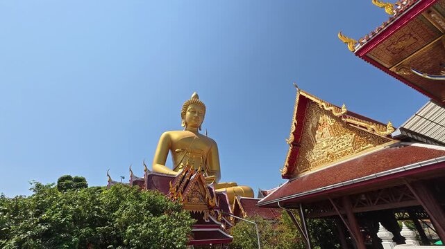 The majestic golden Buddha statue at Wat Paknam Bhasicharoen temple in Bangkok, Thailand, towering above the temple complex in a striking and peaceful setting.