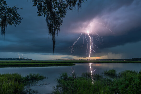 Lightning strikes over Beaufort SC wetlands during a dramatic evening storm with dark clouds and tall grass