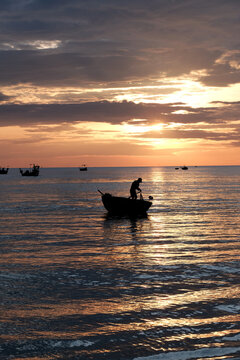 Scenic landscape photograph of fishermen and basket boats on the sea during a vibrant sunrise in a coastal fishing village in Da Nang