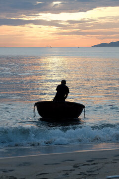ocal fishermen in a coracle heading back to shore under a glowing morning sky
