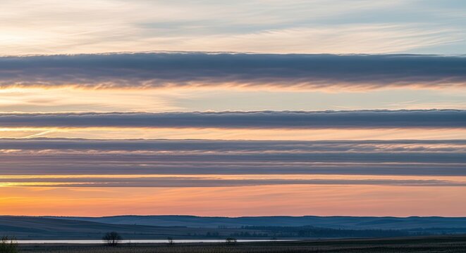 The image captures a serene sunset over a vast, rolling landscape.