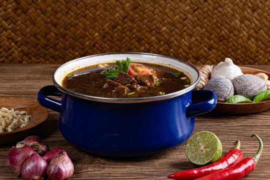 Classic javanese rawon dish with bean sprouts and shallots against woven bamboo background