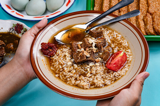 Point of view hands holding traditional nasi rawon street food dish from east java