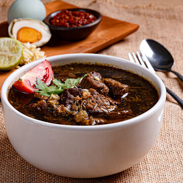 Rustic rawon beef black soup presentation on burlap with wooden serving board