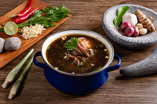 Traditional beef soup setup with indonesian spices on stone mortar and wooden board