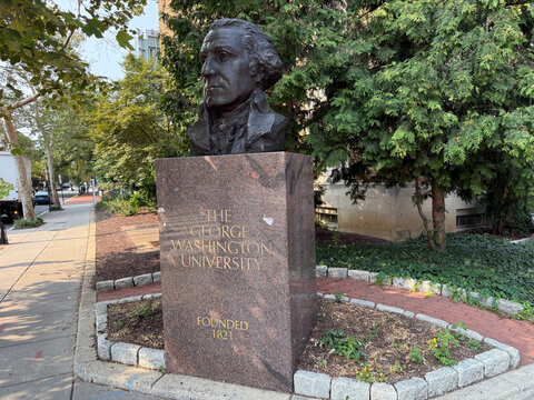 Bronze bust on a stone pedestal bearing George Washington University lettering beside a sidewalk - Washington, District of Columbia, USA - July 27, 2026