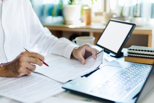 close up shot, asian businessman using laptop and tablet working online checking ducuments and business contract to start new business e-commerce