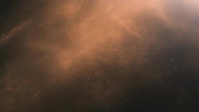 Glowing orange cosmic nebula with dark space and scattered dust particles