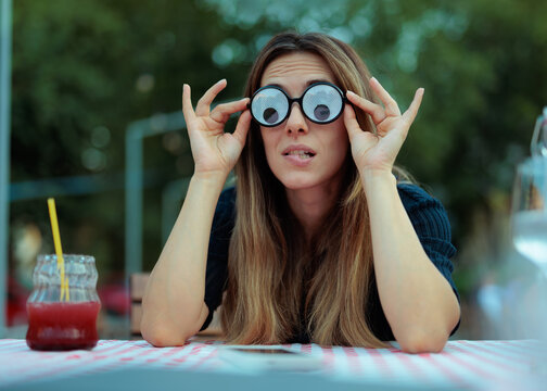 Funny Young Woman Wearing Googly Eyes Glasses Biting Her Lip. Anxious girl poses with silly novelty eyewear while making silly expressions