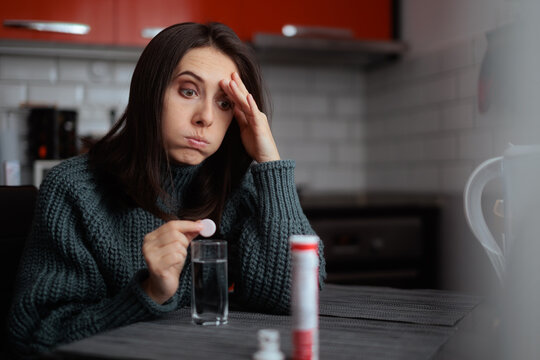 Exhausted  Woman  Holding Effervescent Tablet for Energy. Tired person holds a glass of water while resting taking medication