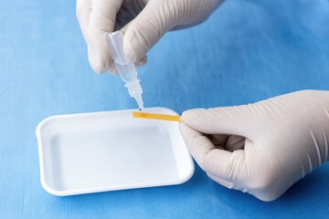 Fototapeta premium Clinician moistening fluorescein strip for eye examination