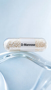 A transparent capsule filled with white powder sits on a smooth glass surface. The label shows the word D-Mannose. Soft light creates a clean setting for the capsule