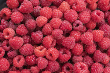 Fresh ripe raspberries photographed close up as a natural food background. Detailed texture of juicy berries representing healthy eating and summer harvest. © Olha
