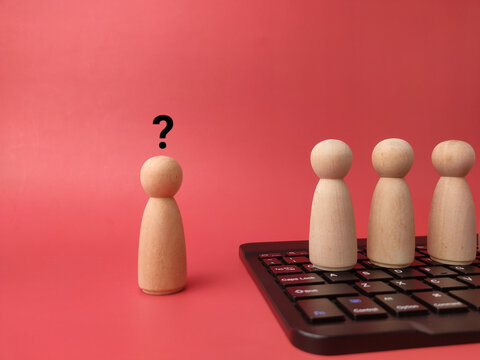A wooden peg figure with a question mark stands apart from three figures on a computer keyboard
